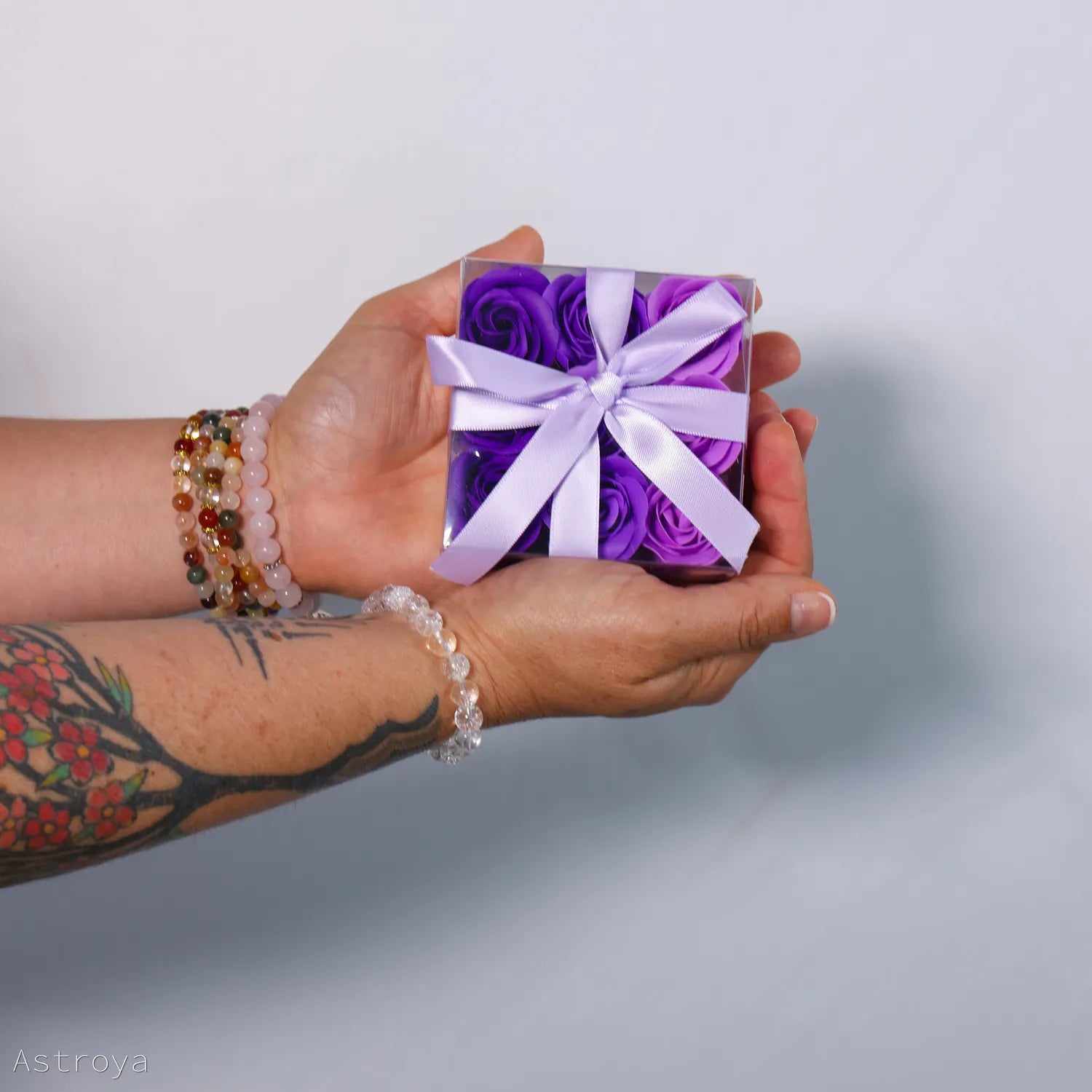 Boite de 9 fleurs de savon, des roses, tenue dans la main. Variations de violet.