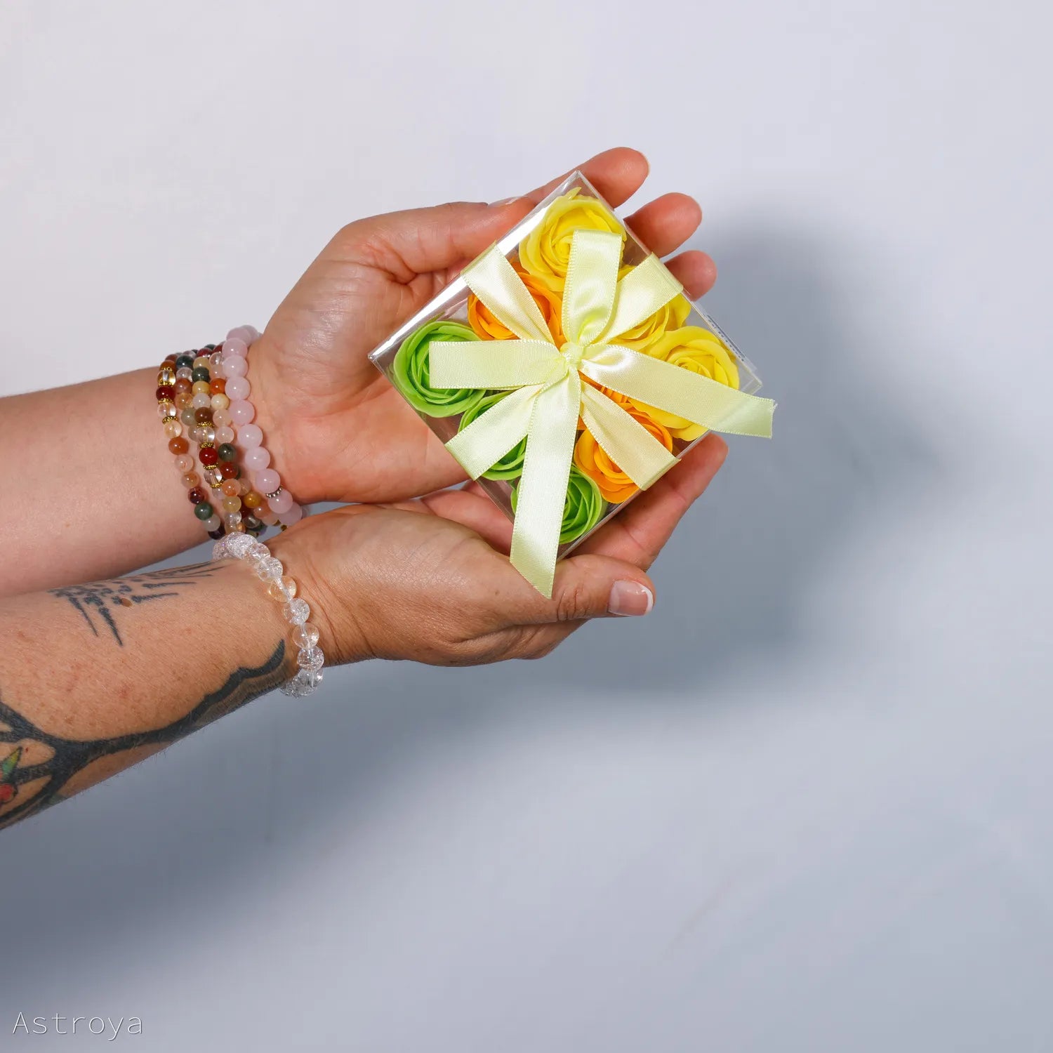 Boite de 9 roses de savon tenue dans la main. Couleur jaune orangé, jaune et vert