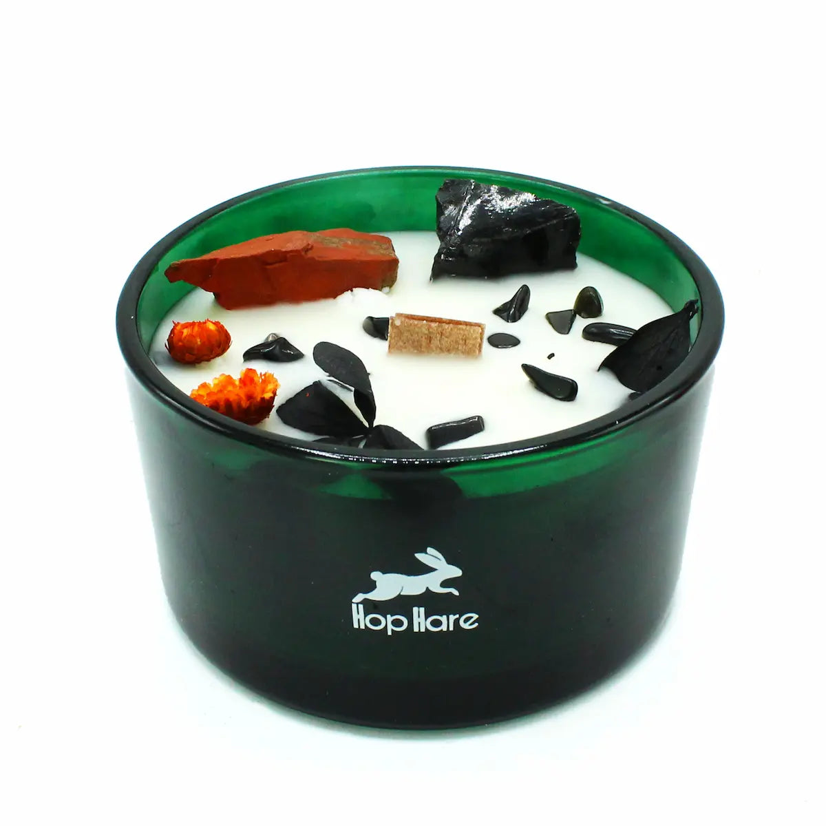 Gros plan bougie Le Diable parfum brasier en pleine floraison avec pierres de jaspe rouge et agate noire