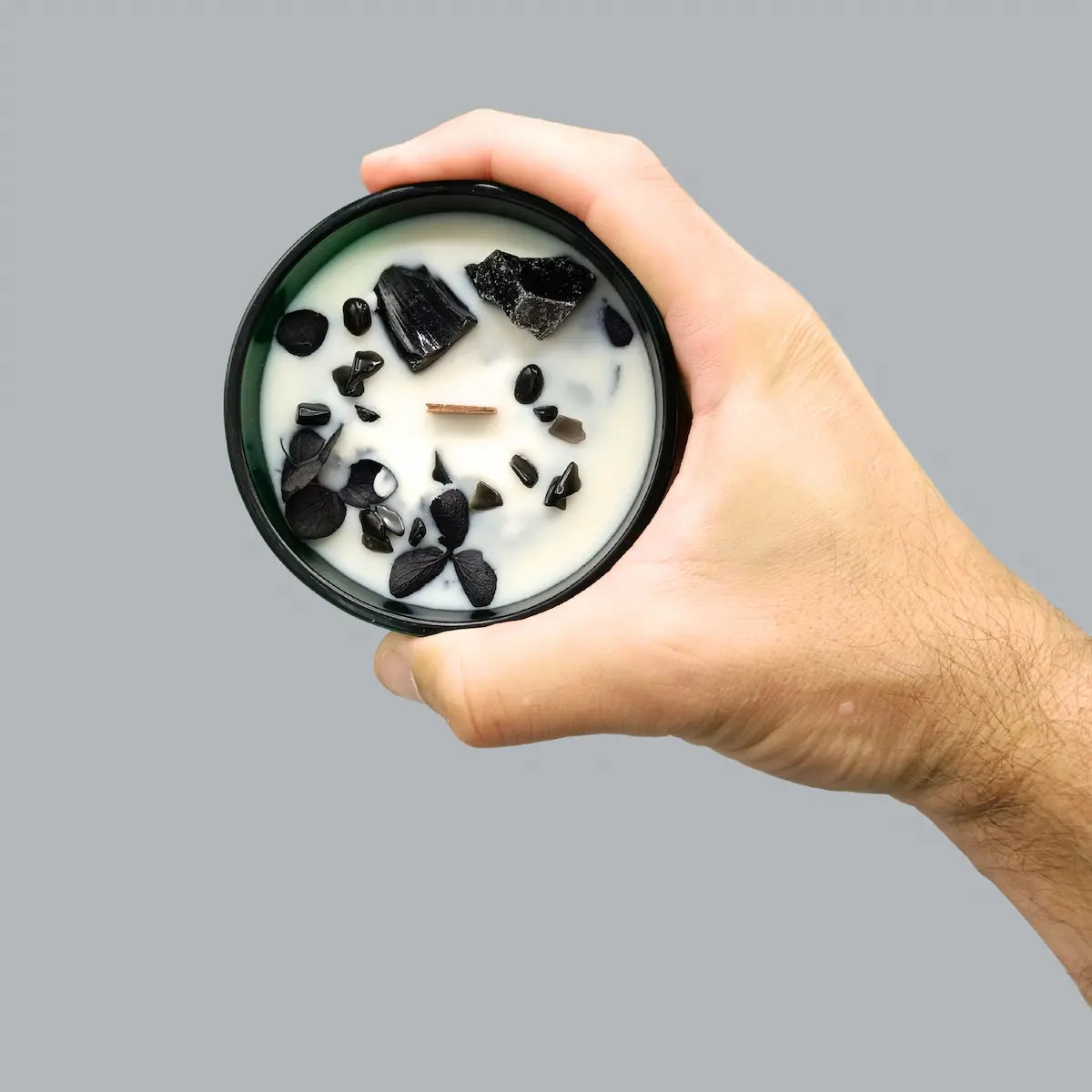 Gros plan bougie Le Chevalier des Épées parfum cèdre et patchouli avec pierres obsidienne noire et fleurs séchées