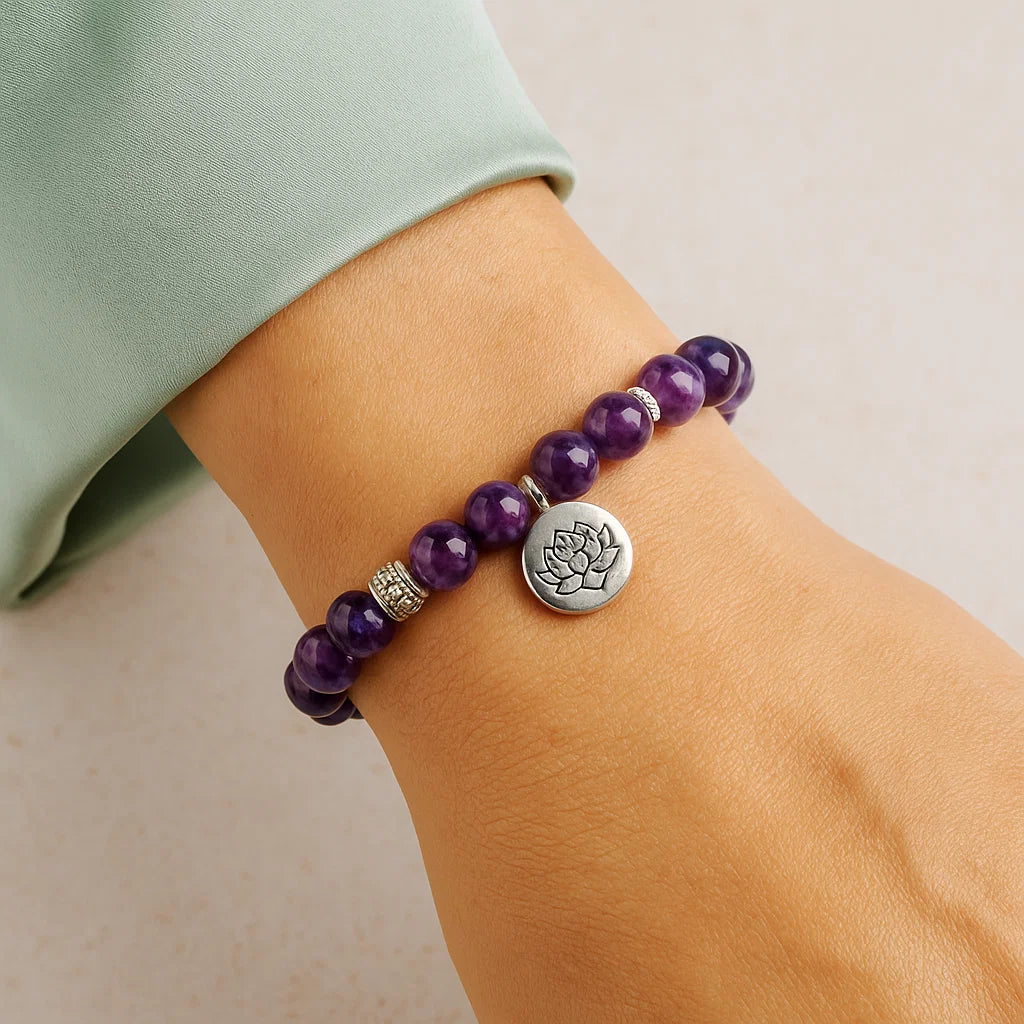 Bracelet en améthyste naturelle porté au poignet avec médaille lotus, accessoire lithothérapie pour équilibre émotionnel