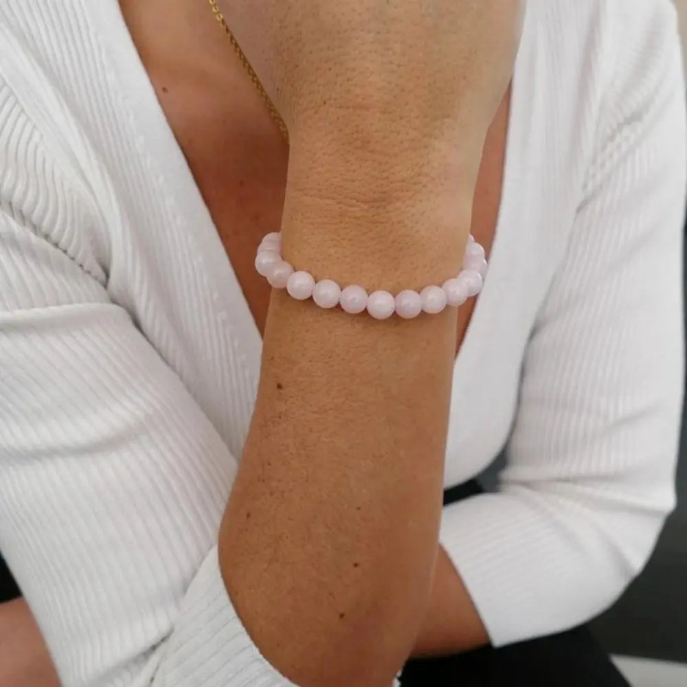 Bracelet en quartz rose porté au poignet, pierres naturelles symbolisant l’amour, la paix intérieure et la douceur émotionnelle