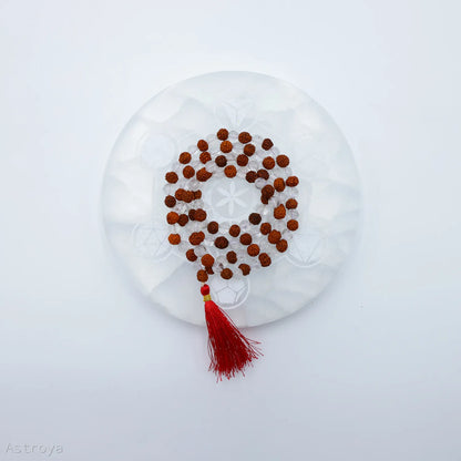 Mala Cristal de Roche - Rudraksha | 108 perles sur une pierre de chargement en sélénite - vue de dessus