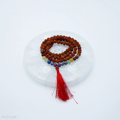 Mala Rudraksha 7 chakras sur une pierre de chargement en sélénite disponible également sur Astroya.fr