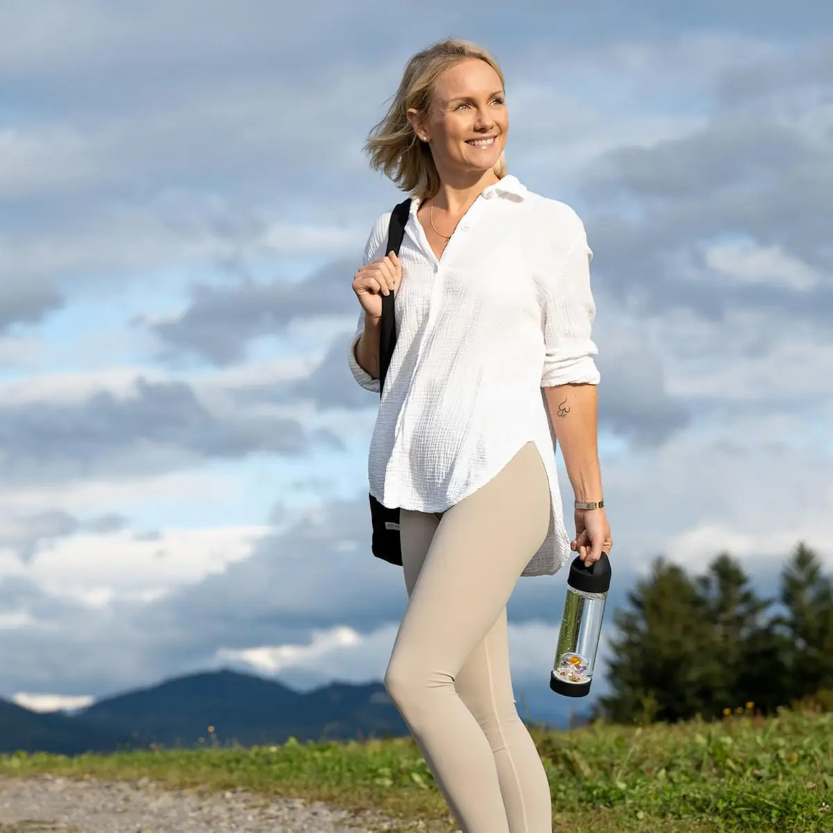 Femme souriante tenant la bouteille en verre borosilicate VitaJuwel ViA Prana Noire avec pierres précieuses