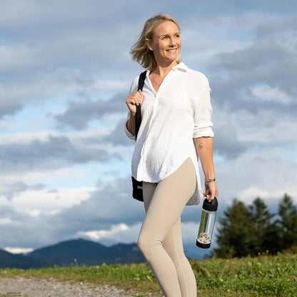 Femme souriante tenant la bouteille en verre borosilicate VitaJuwel ViA Prana Noire avec pierres précieuses