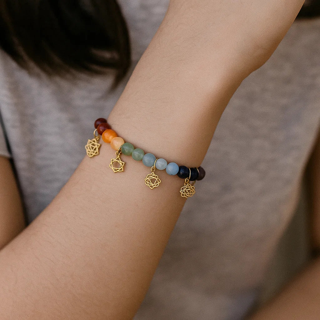 Bracelet avec breloques de symboles des chakras et pierres des chakras porté par une femme