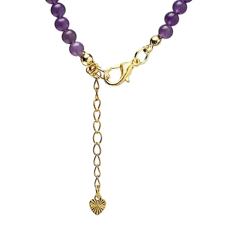 Détail pendentif soleil doré sur collier de perles améthyste style spirituel et bohème